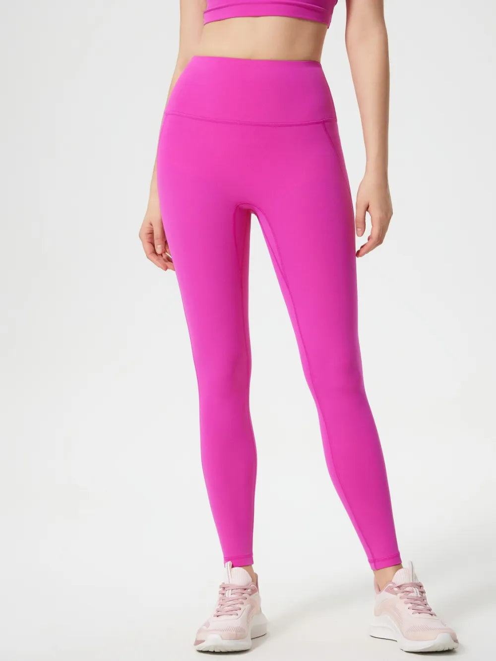 Person wearing bright pink leggings on a white background