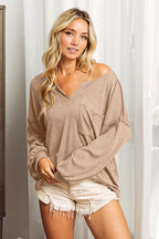 Woman wearing a beige sweater and white shorts indoors.