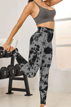 Person wearing a gray sports bra and tie-dye leggings in a gym setting.