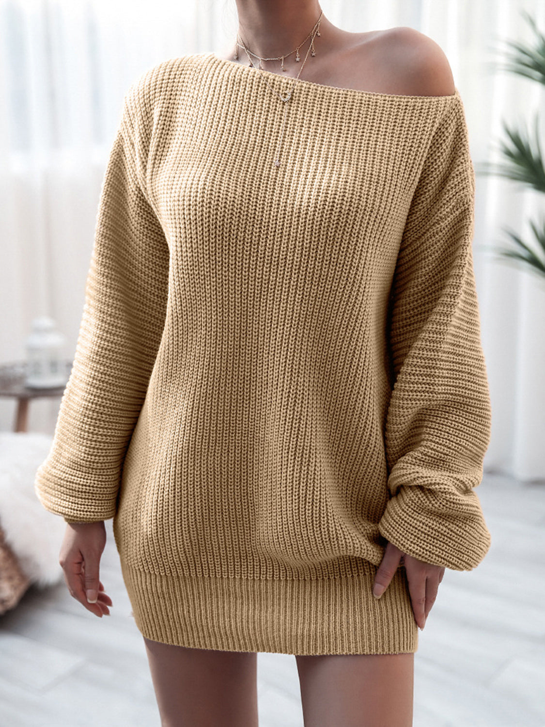 Beige knitted sweater worn by a person in a softly blurred indoor setting