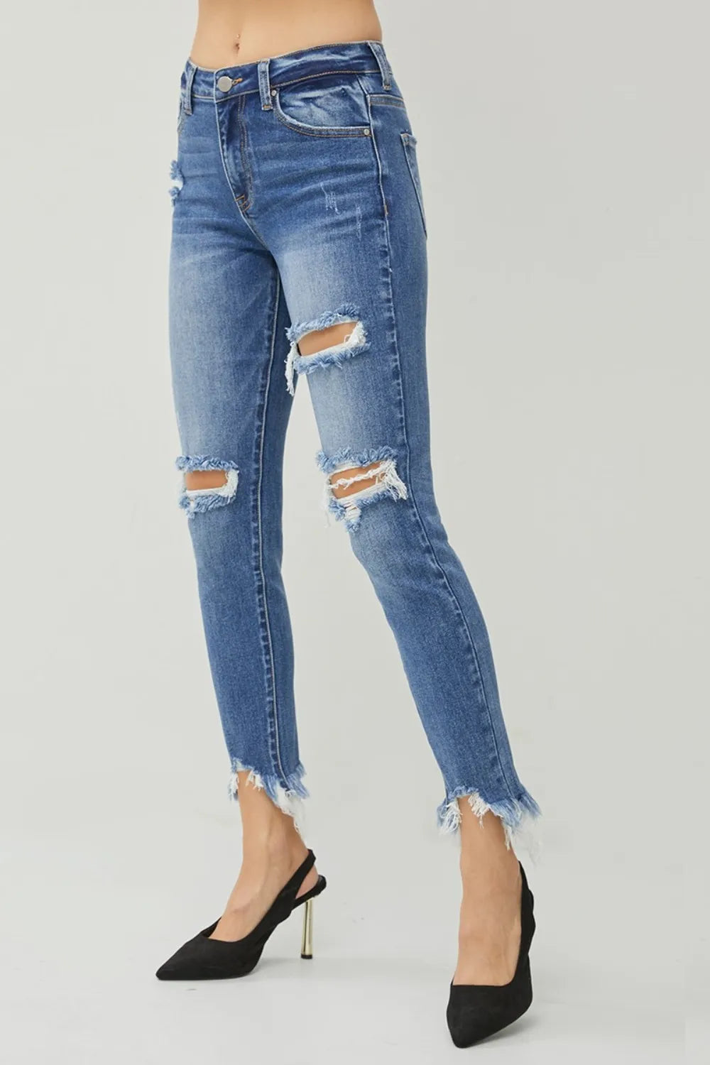 Ripped blue jeans worn by a person on a gray background