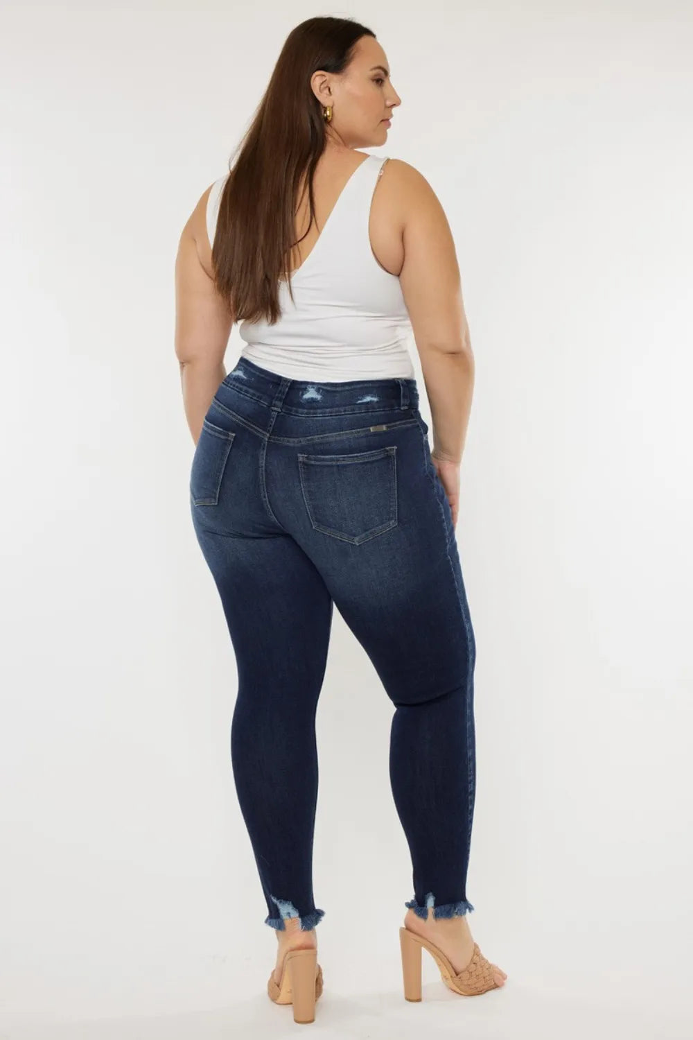 Woman wearing dark blue jeans and a white top on a white background