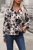 Woman wearing a black floral blouse and blue jeans outdoors.