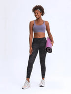 Woman in athletic wear holding a pink yoga mat on a white background