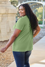 Woman wearing a green t-shirt and blue jeans standing outdoors.