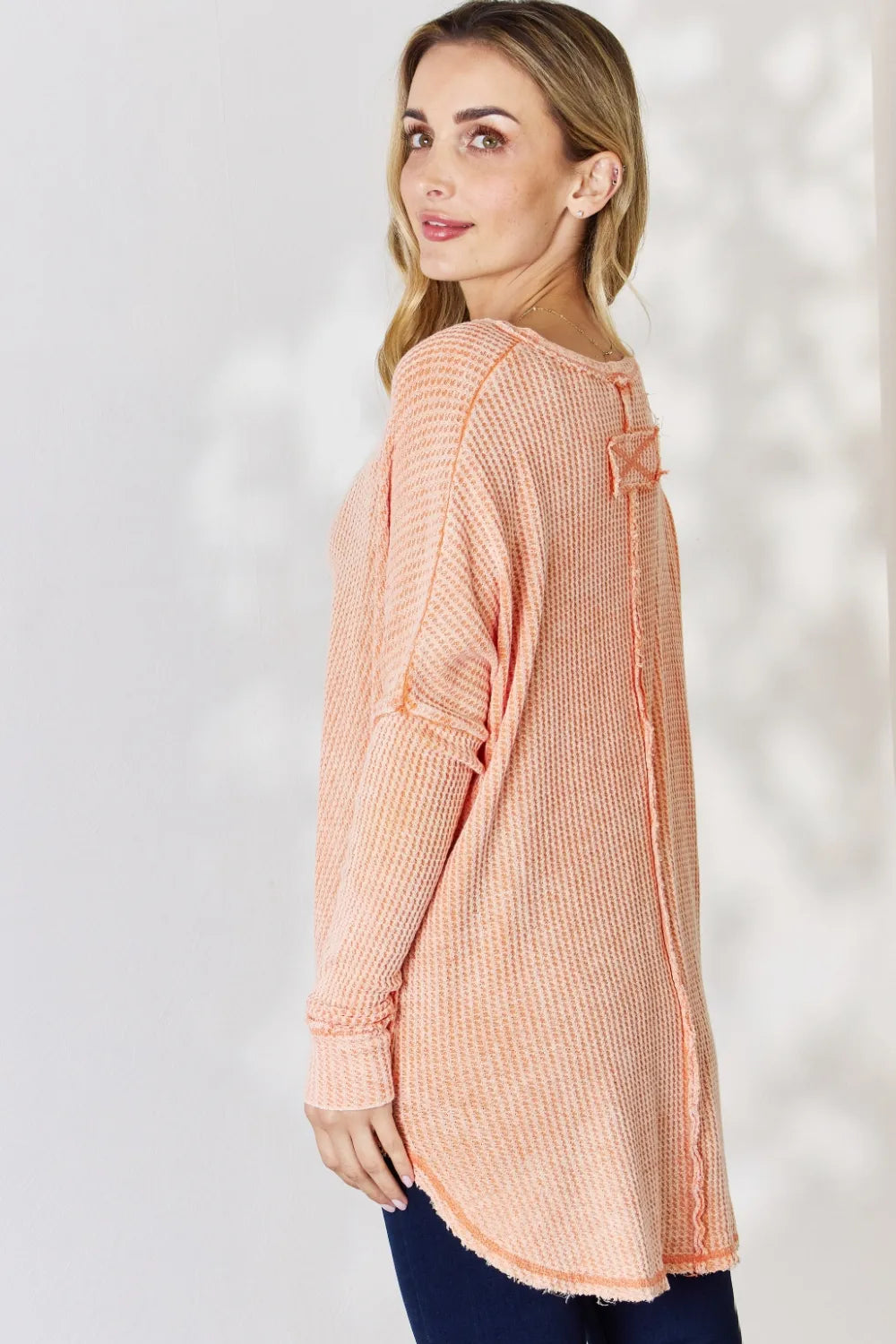 Woman wearing a peach-colored textured top against a white background