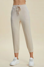 Beige jogger pants worn by a person on a beige background
