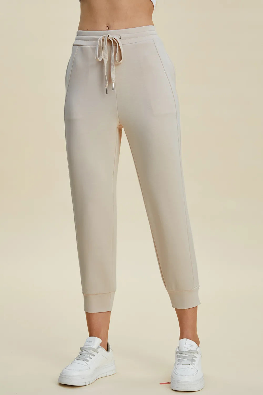 Beige jogger pants worn by a person on a beige background