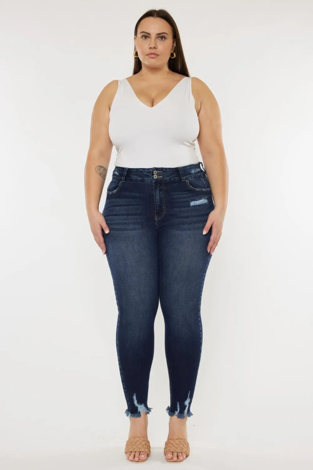 Woman wearing a white top and dark blue jeans on a white background