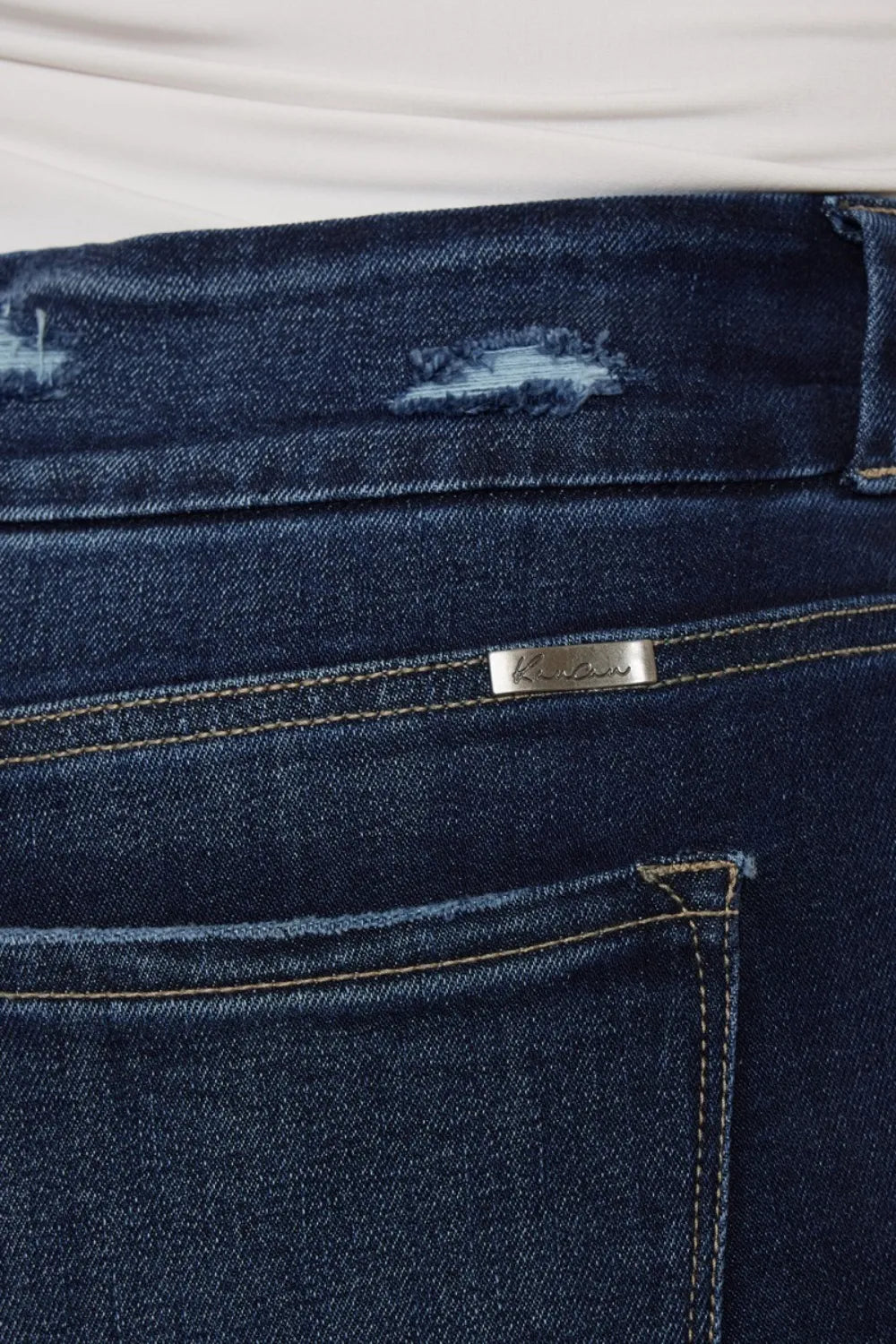 Close-up of dark blue jeans with a brand label on the back pocket.