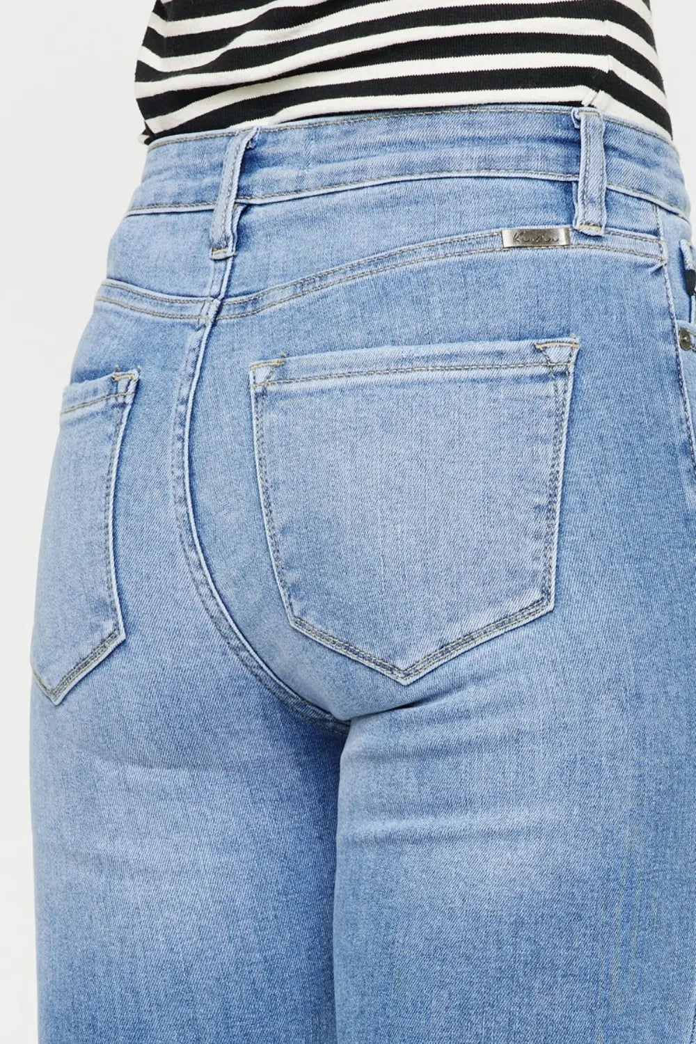 Close-up of blue jeans with a striped shirt underneath