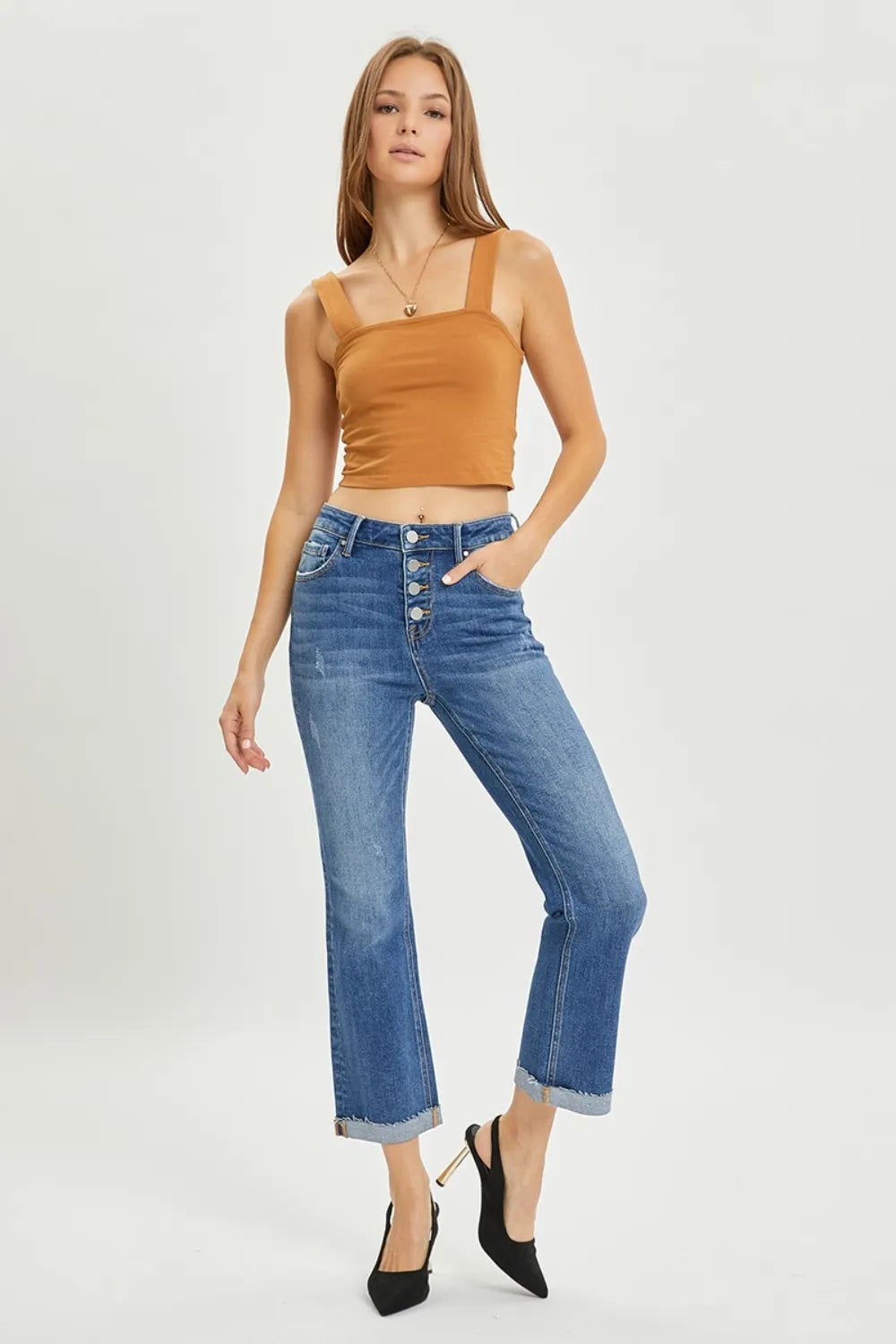 Woman wearing a mustard yellow top and blue jeans on a white background
