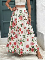 Person wearing a white top and floral skirt with red roses against a blue door.
