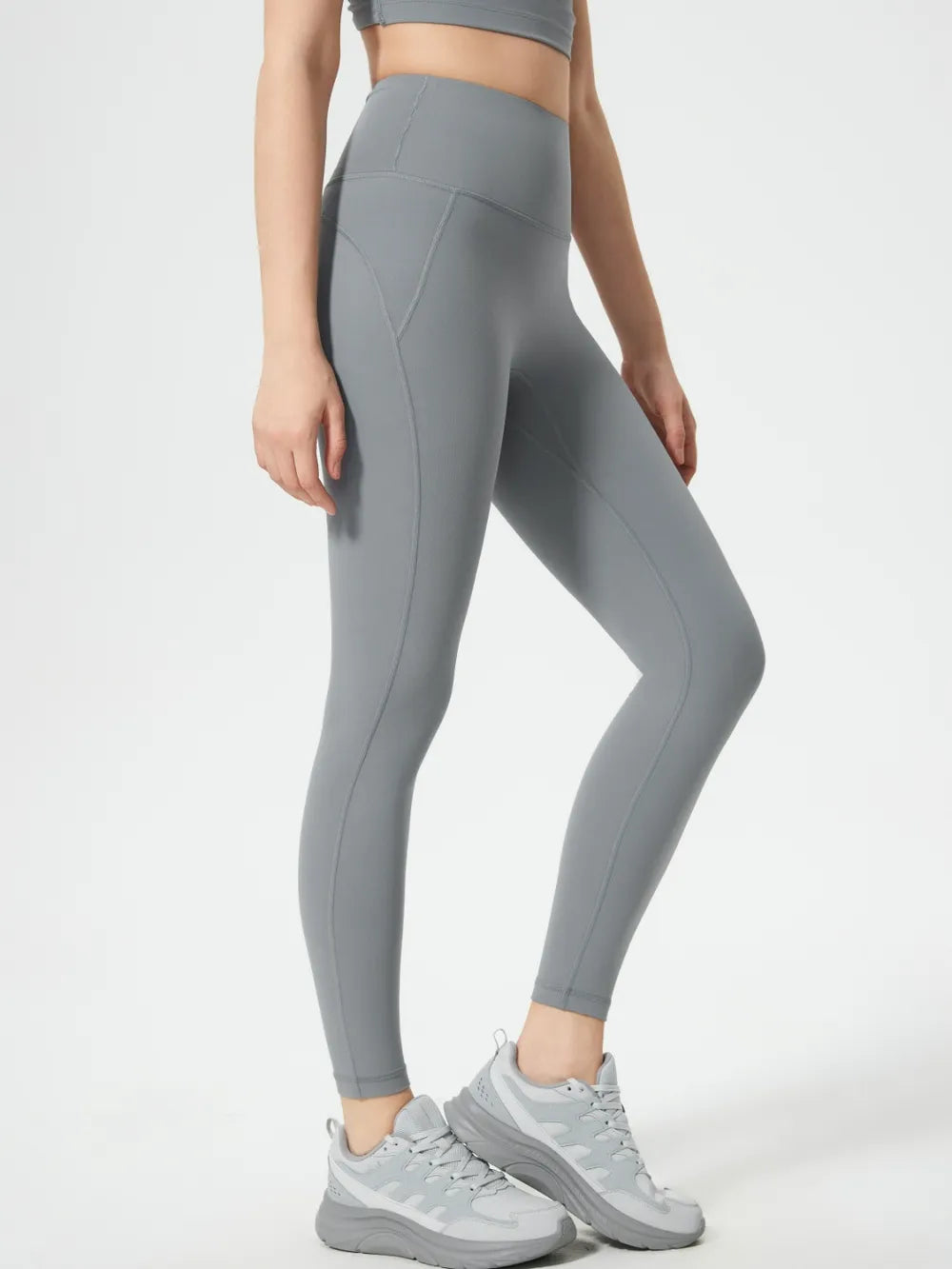 Person wearing gray leggings and sneakers on a white background