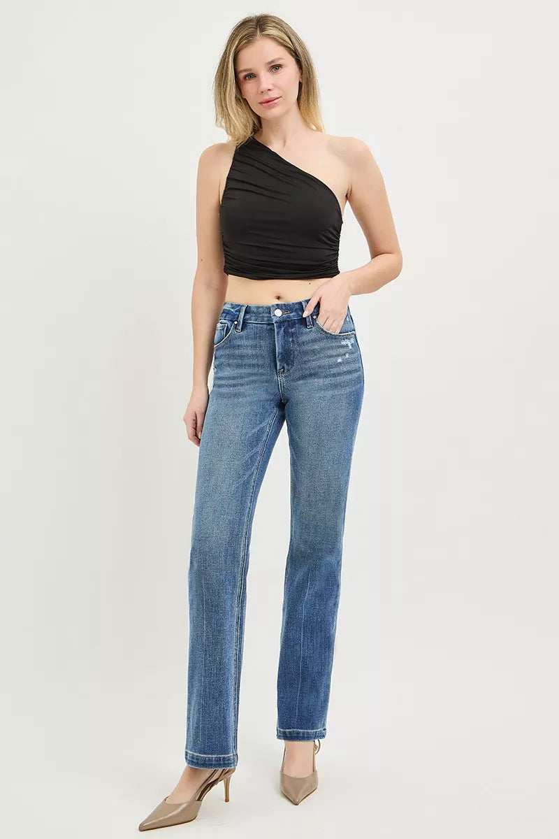 Woman wearing a black one-shoulder top and blue jeans on a white background