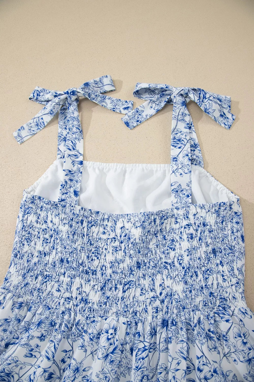 Blue floral dress with white straps on a beige background