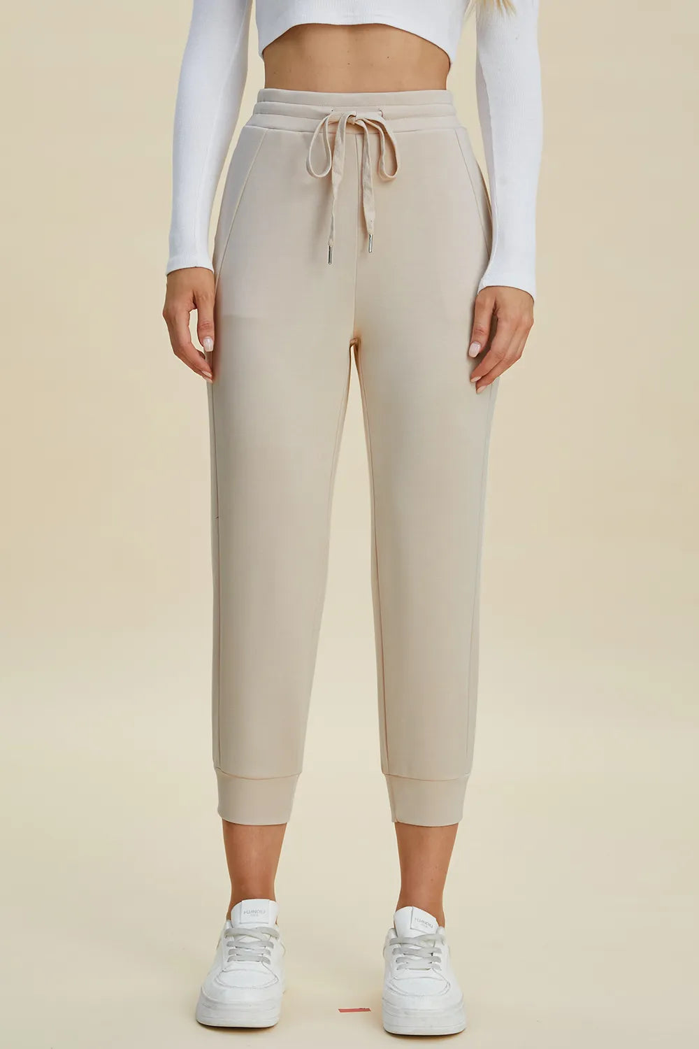 Beige jogger pants worn by a person on a beige background