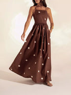 Woman wearing a brown dress with white polka dots on a plain background