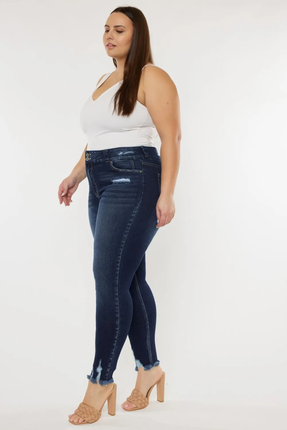 Woman wearing dark blue jeans and a white top on a white background