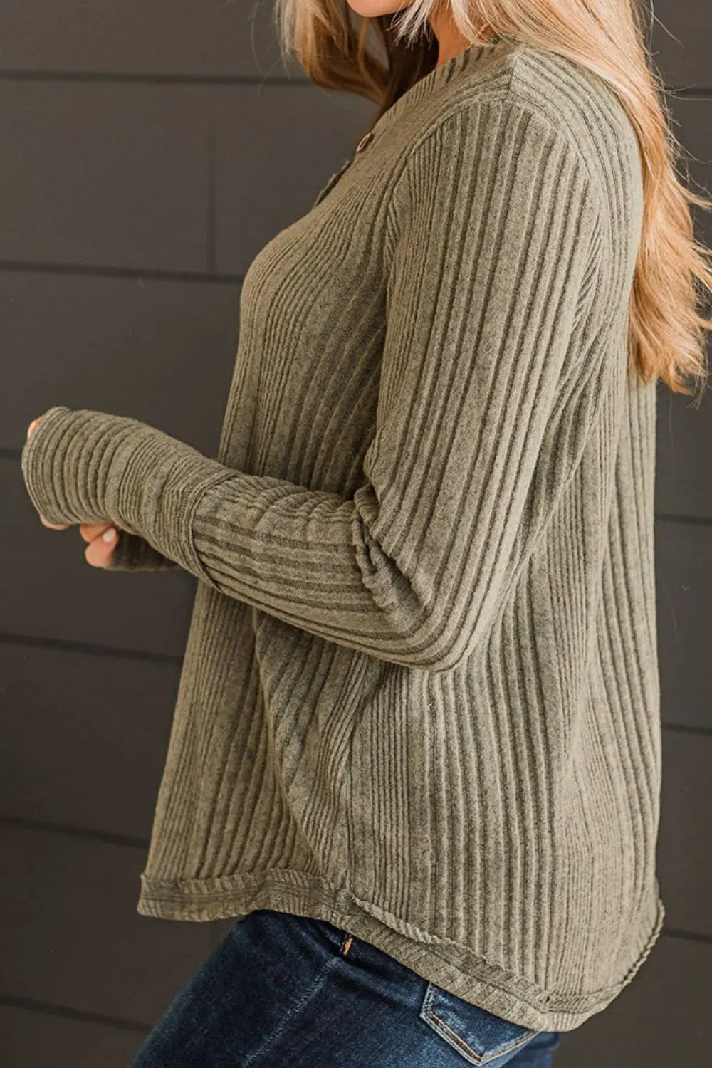 Person wearing a green ribbed sweater against a dark background