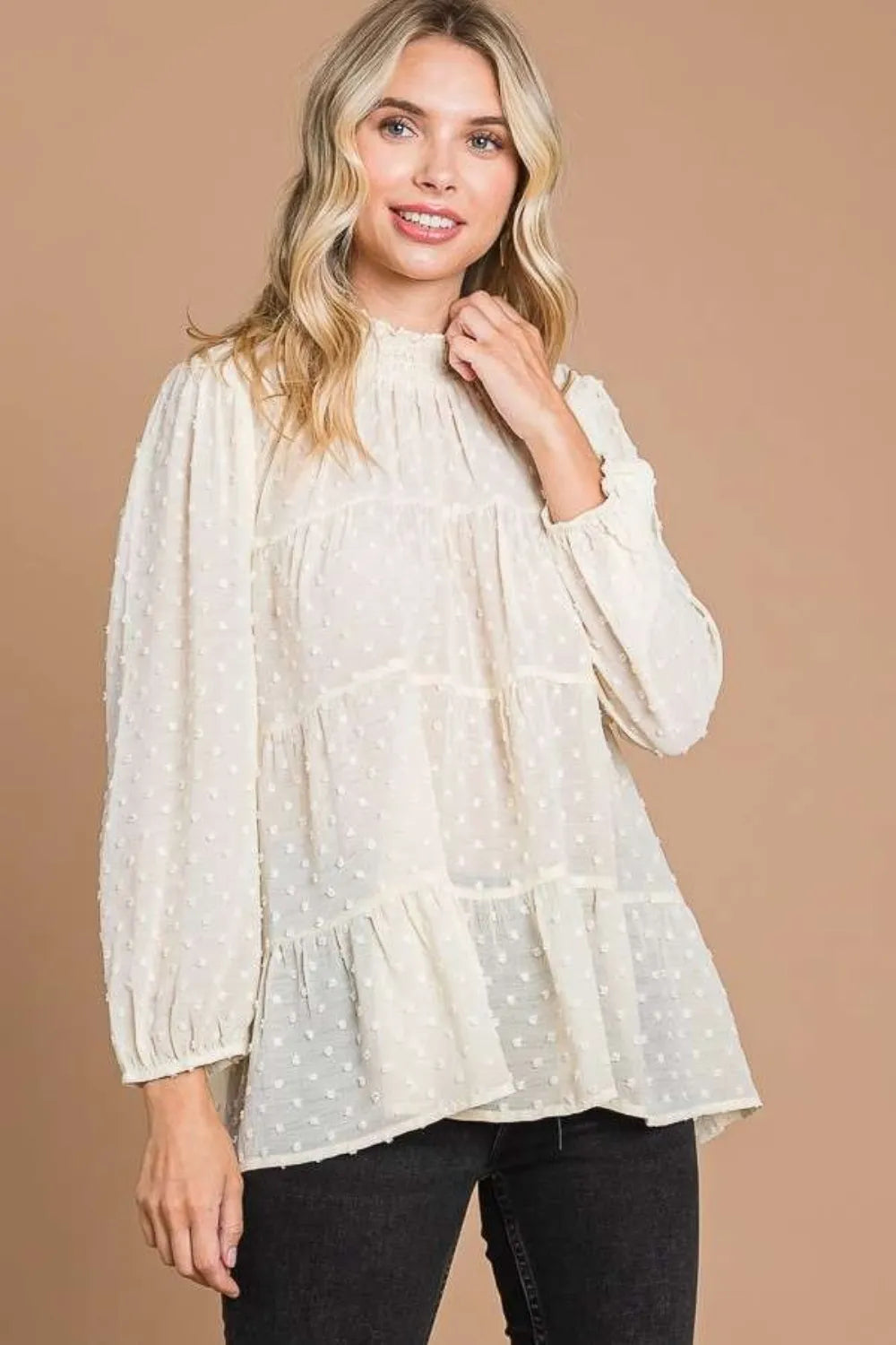 Woman wearing a white polka dot blouse against a beige background