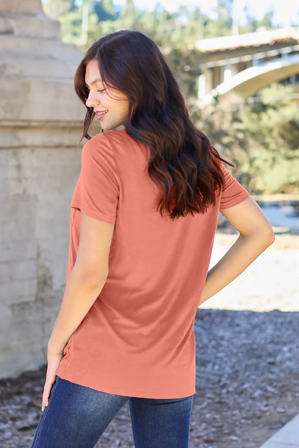 Woman wearing a rust-colored t-shirt outdoors with blurred background
