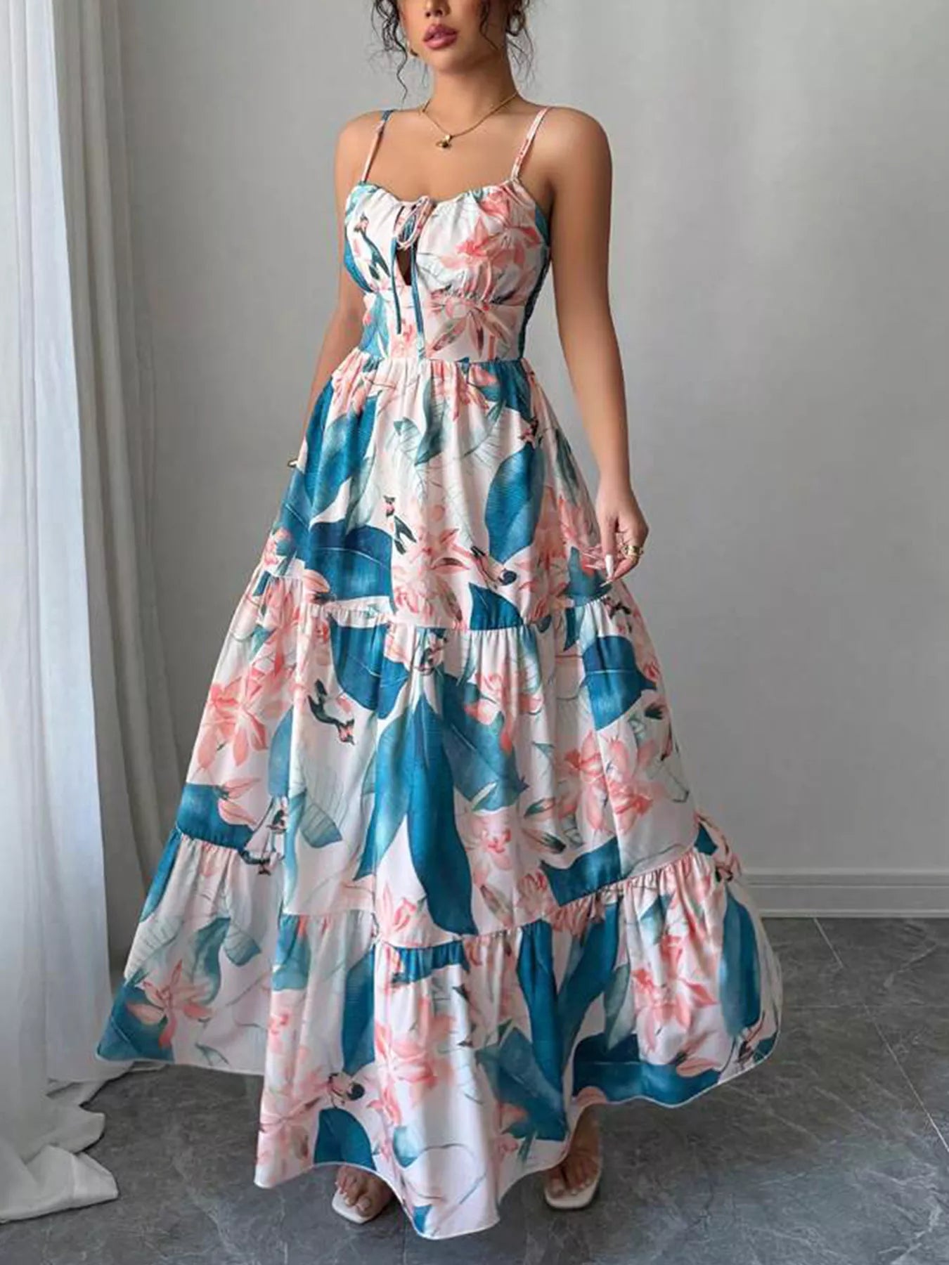 Woman wearing a floral dress with blue and pink patterns in a minimal indoor setting.