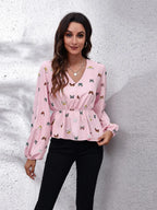 Woman wearing a pink blouse with butterfly pattern against a textured white wall