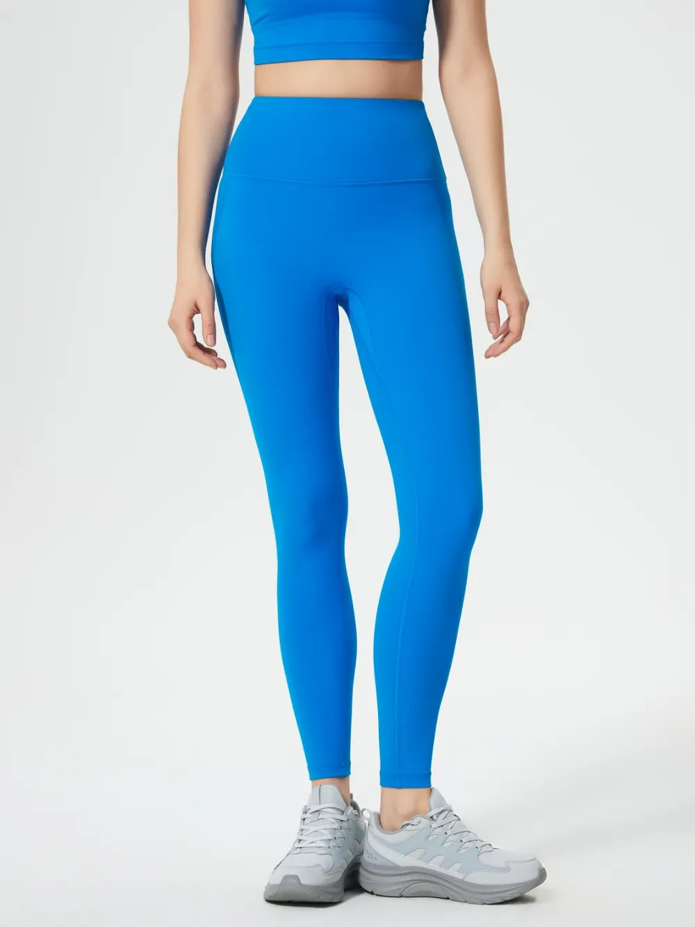 Person wearing bright blue leggings and a matching top on a white background