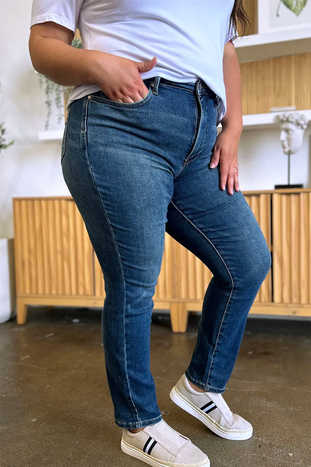 Person wearing blue jeans and white sneakers in a kitchen setting