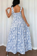 Woman wearing a blue floral dress against a white curtain background
