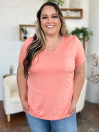 Woman wearing a peach-colored t-shirt with a pocket in a home setting