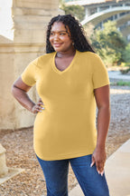 Woman wearing a yellow t-shirt and blue jeans standing outdoors with a blurred background