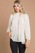 Woman wearing a white blouse with long sleeves against a beige background
