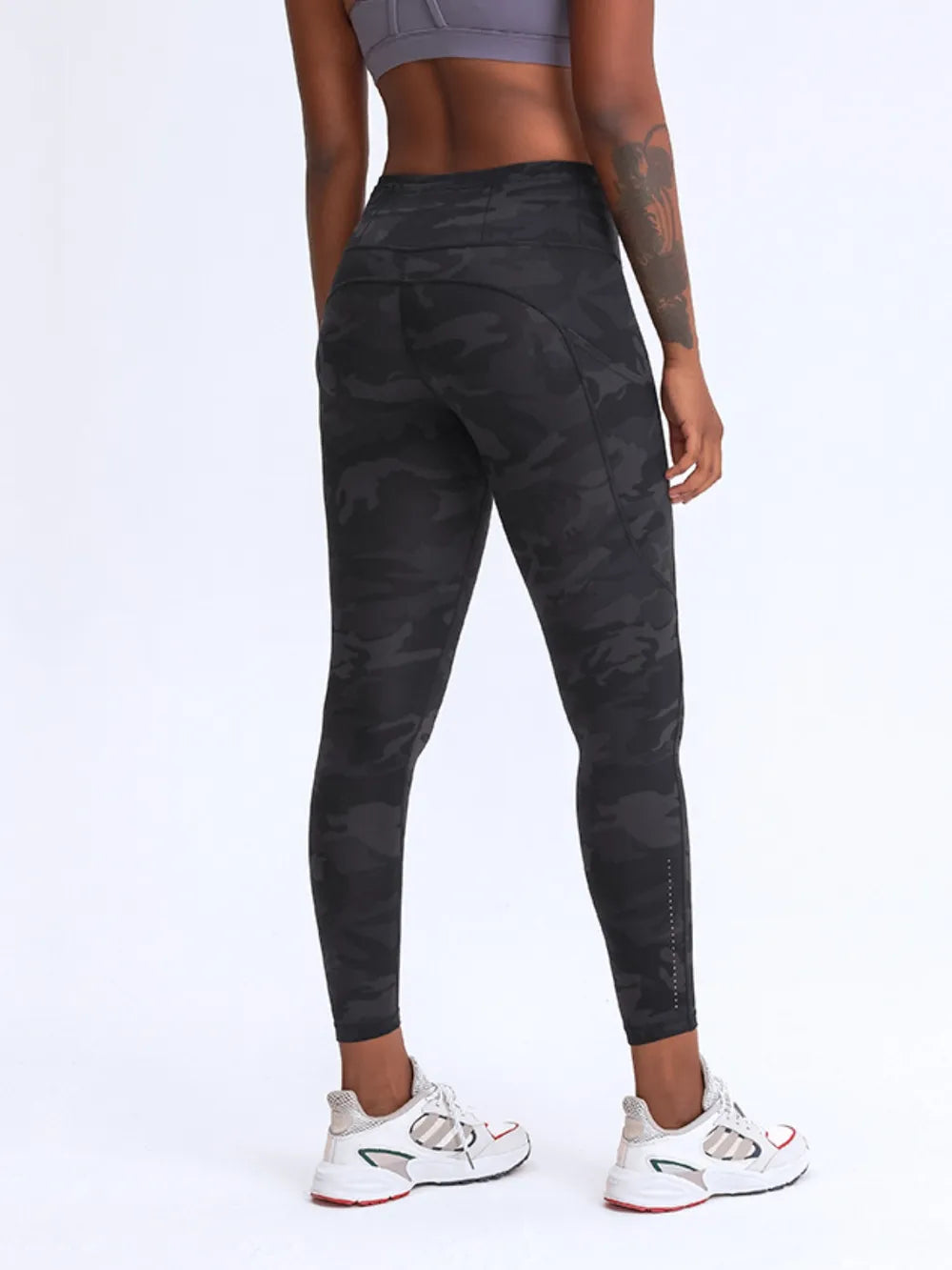 Person wearing black camouflage leggings on a white background