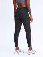 Person wearing black camouflage leggings on a white background