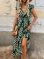 Woman wearing a green and white patterned dress against a rustic wall.