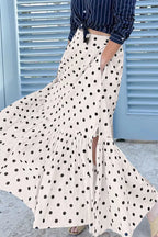 Person wearing a white polka dot skirt with a blue background
