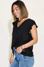 Woman wearing a black top and blue jeans against a plain background