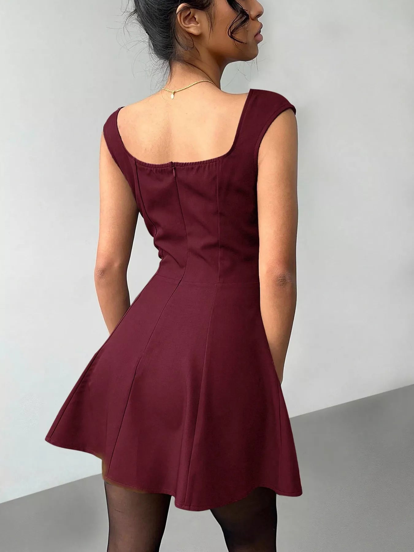 Woman wearing a burgundy dress against a plain background