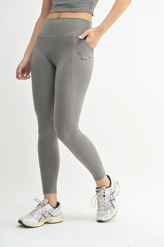 Person wearing gray leggings and athletic shoes on a white background
