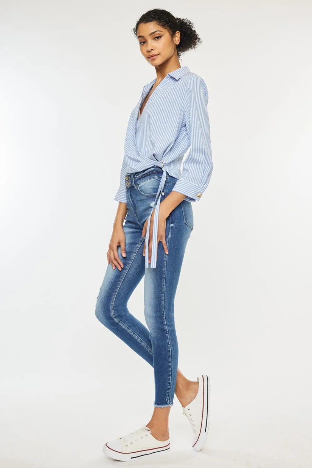 Woman wearing a light blue striped shirt and blue jeans on a white background