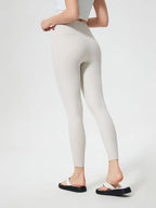 Person wearing white leggings on a plain background