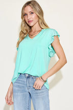 Woman wearing a light blue top and jeans against a plain background