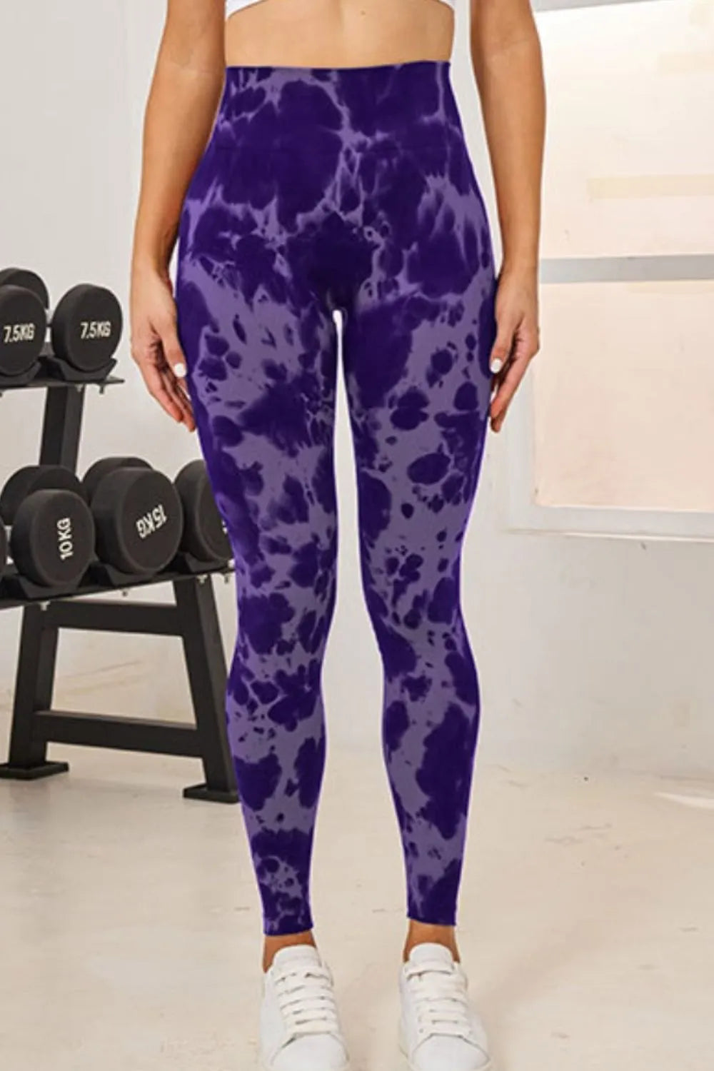 Person wearing purple tie-dye leggings in a gym setting