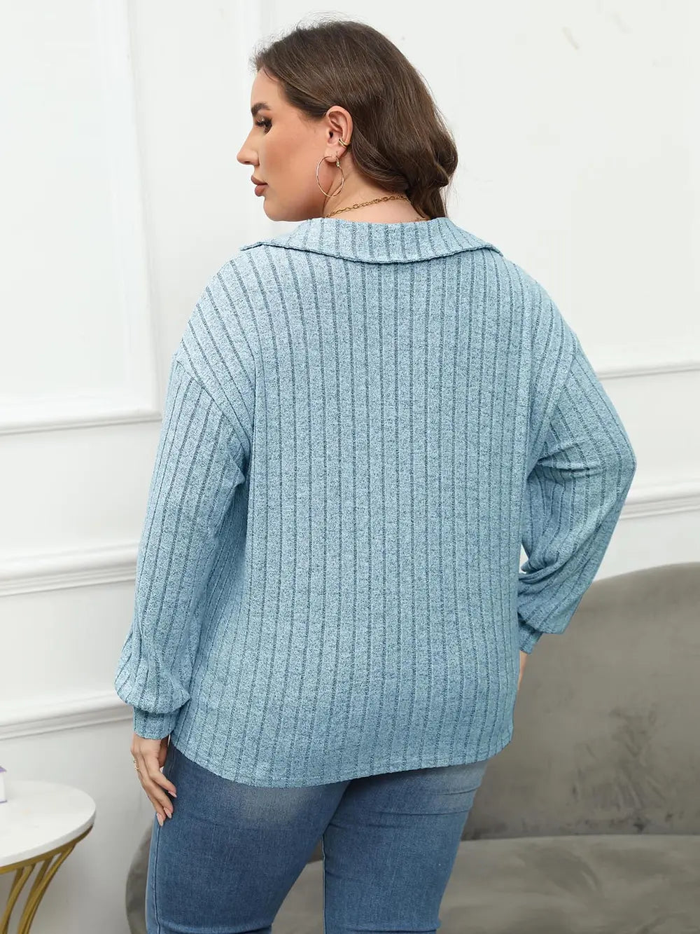 Woman wearing a blue textured sweater and jeans in an indoor setting