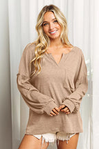 Woman wearing a beige long-sleeve top with a neutral background