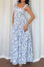 Woman wearing a blue floral dress against a white curtain background