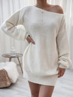 Person wearing a white off-shoulder sweater dress in a minimalistic room.