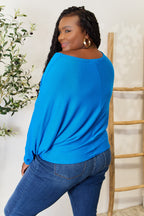Woman wearing a blue sweater and jeans standing in a room with a plant and wooden ladder.